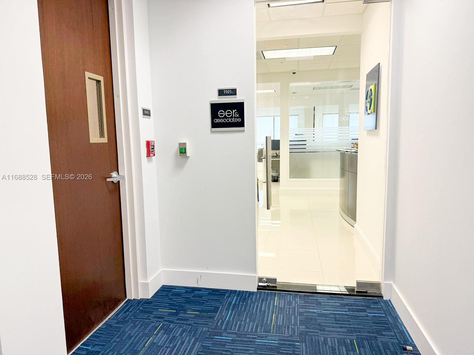 A commercial office entrance features a wood door, blue carpet, and a glass-paneled doorway — 2020 Ponce De Leon Blvd, Coral Gables FL 33134, CORAL GABLES, FL