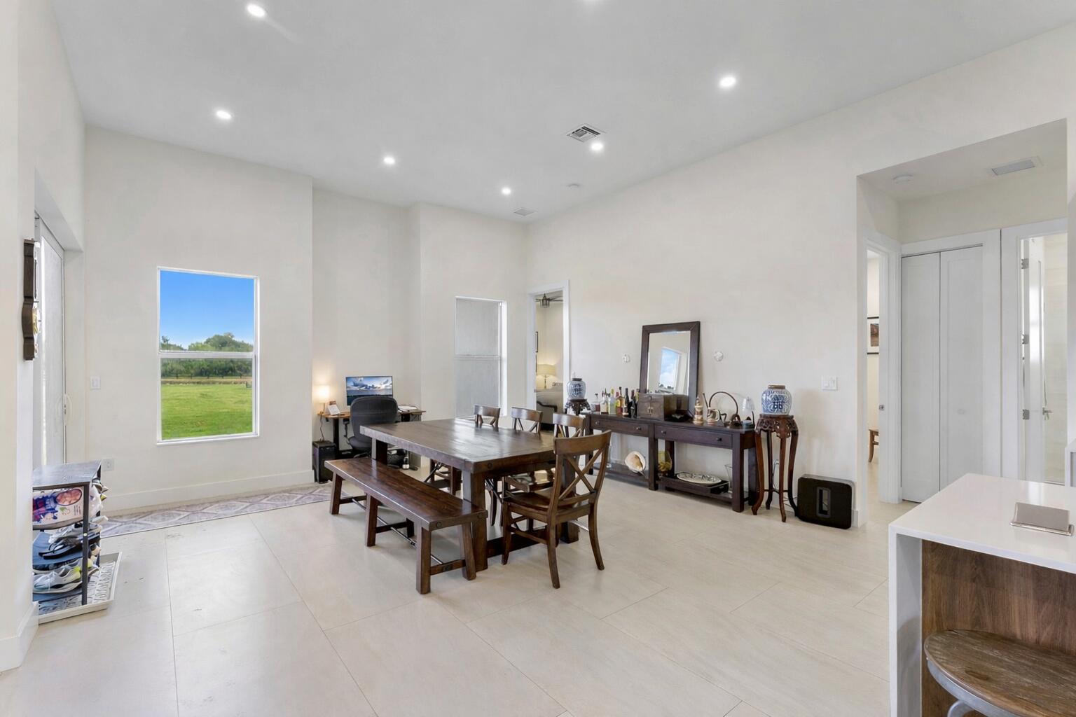 A dining room with a wooden table, bench, chairs, and a console table on tile floors — 19921 Skyhawk Lane, FL 33470, FL
