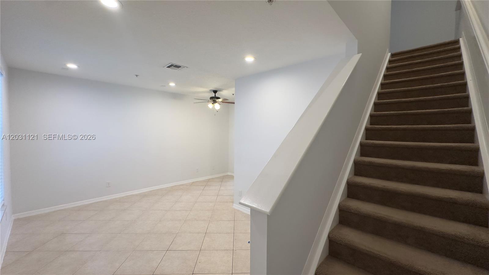 An interior view shows a tiled living area with a ceiling fan and carpeted stairs — 1587 Frederick Small Rd, Jupiter FL 33458, JUPITER, FL