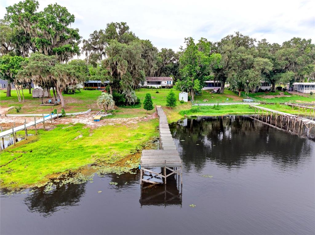 An aerial view shows a wooden dock extending into a lake near several houses — 125 ANN STREET, HAWTHORNE, FL