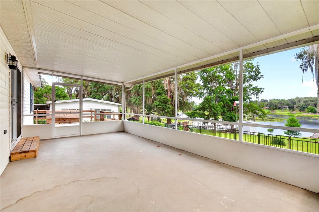 A screened-in porch with a concrete floor overlooks a lake and trees — 125 ANN STREET, HAWTHORNE, FL