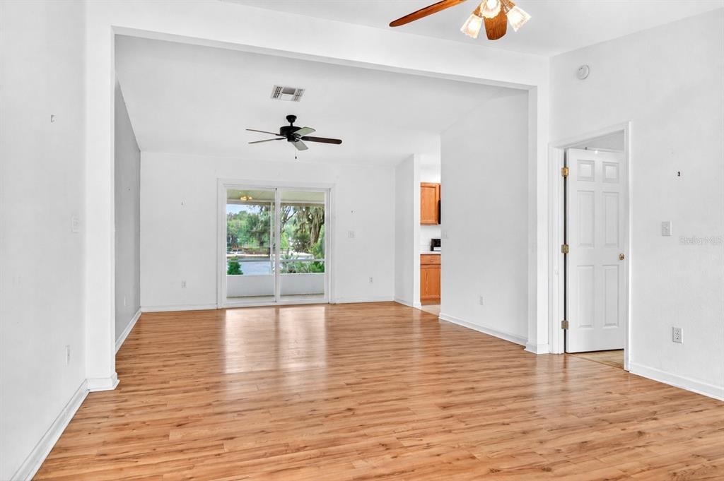 An empty living room with wood-look flooring, white walls, a ceiling fan, and sliding doors — 125 ANN STREET, HAWTHORNE, FL
