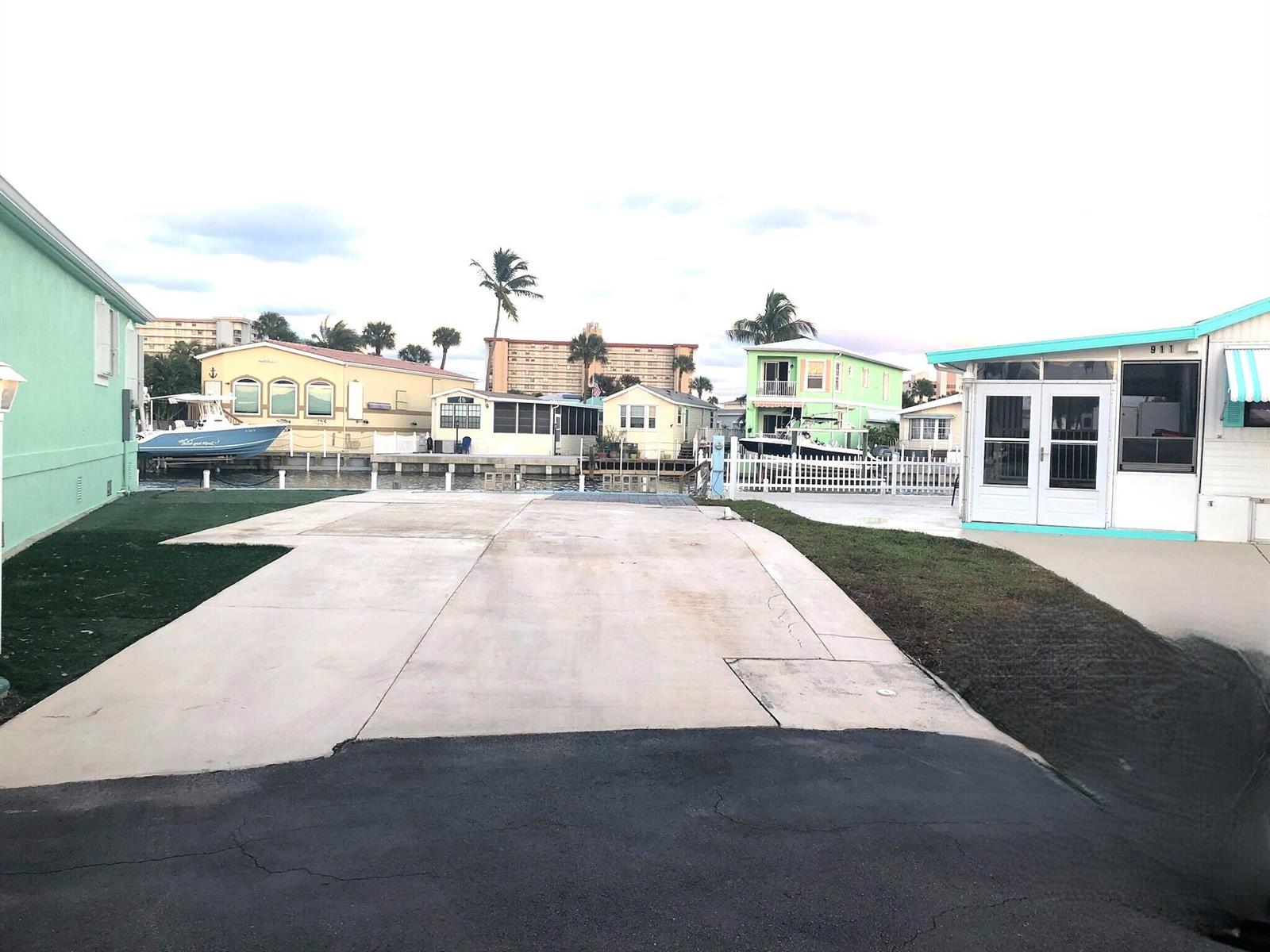 A paved driveway leads toward a canal with several waterfront homes and docked boats — 10701 S Ocean Drive, Jensen Beach FL 34957, JENSEN BEACH, FL