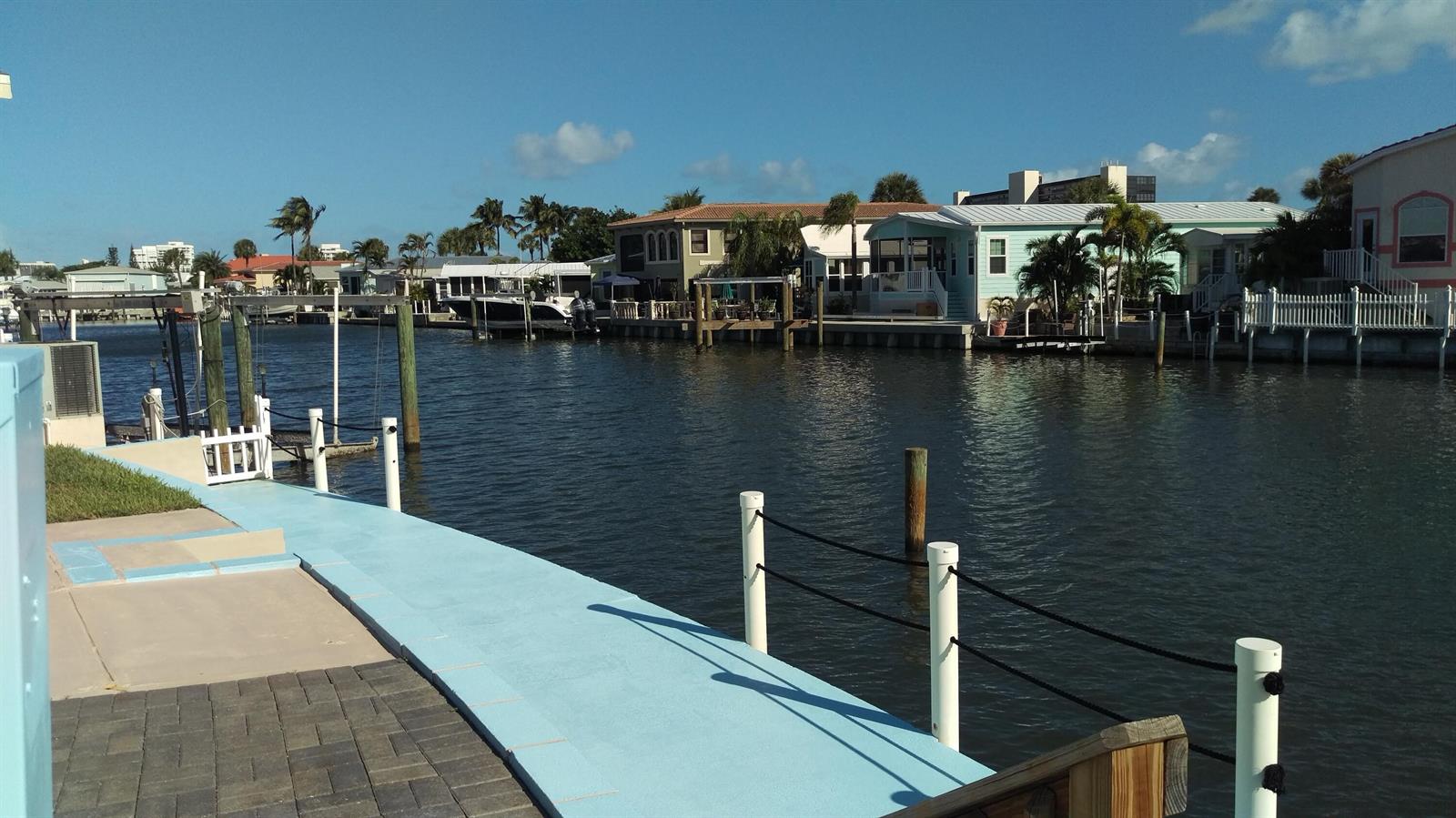 A view of a canal with waterfront homes, boat docks, and a blue paved walkway — 10701 S Ocean Drive, Jensen Beach FL 34957, JENSEN BEACH, FL