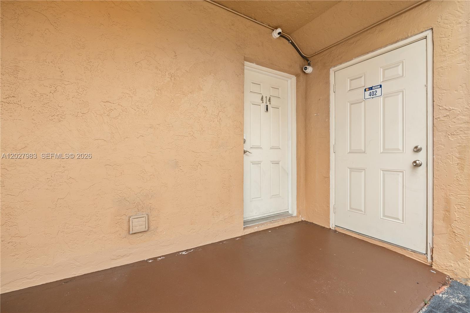 Two white doors labeled 414 and 402 are set in a tan stucco exterior wall — 9950 SW 88th St # 4, Miami FL 33176, MIAMI, FL