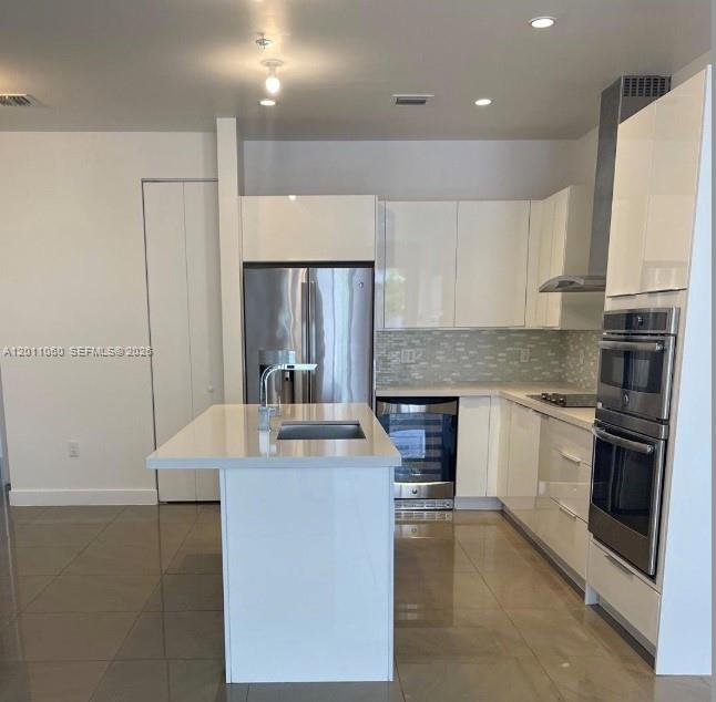 A modern kitchen features white glossy cabinets, stainless steel appliances, and a central island — 10245 NW 63rd Ter # 103, Doral FL 33178, DORAL, FL