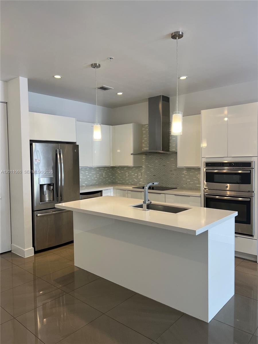 A modern kitchen features white cabinets, stainless steel appliances, and a central island with sink — 10245 NW 63rd Ter # 103, Doral FL 33178, DORAL, FL