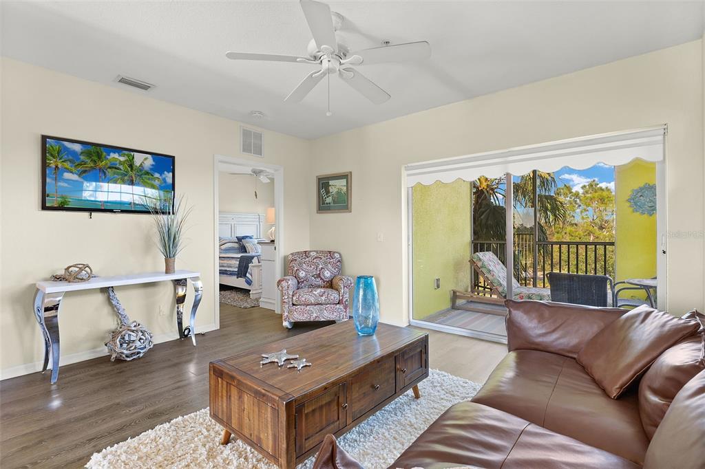 A living room features a brown leather sofa, wooden coffee table, and sliding glass balcony doors — 2060 WILLOW HAMMOCK CIRCLE UNIT D304, PUNTA GORDA, FL