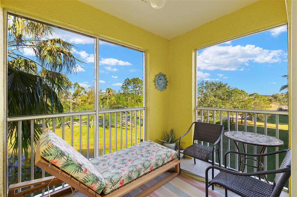 A screened-in balcony with yellow walls, a lounge chair, and a small table and chairs — 2060 WILLOW HAMMOCK CIRCLE UNIT D304, PUNTA GORDA, FL