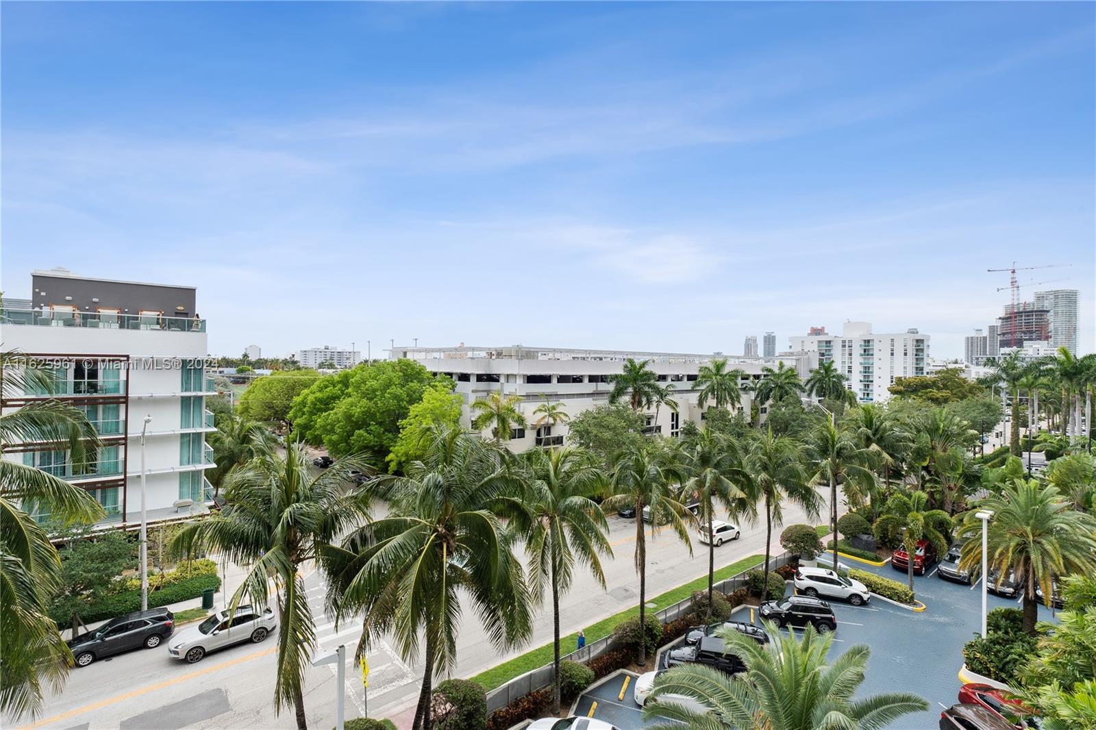 An elevated view shows a street with palm trees, parked cars, and nearby apartment buildings — 1200 West Ave # 515, Miami Beach FL 33139, MIAMI BEACH, FL