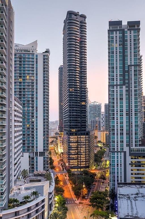 An elevated view of several tall, modern glass skyscrapers surrounding a street at dusk — 1000 Brickell Plz # 2705, Miami FL 33131, MIAMI, FL
