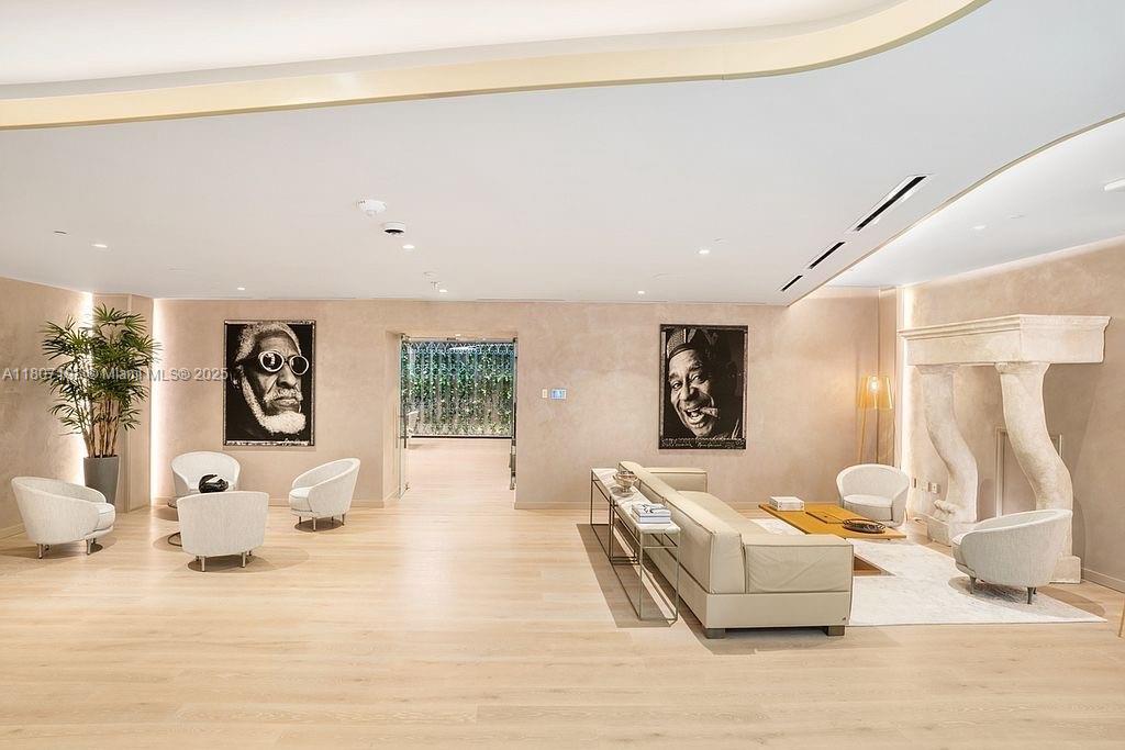 A spacious, minimalist living room features light wood floors, two portrait photographs, and a fireplace — 1000 Brickell Plz # 2705, Miami FL 33131, MIAMI, FL