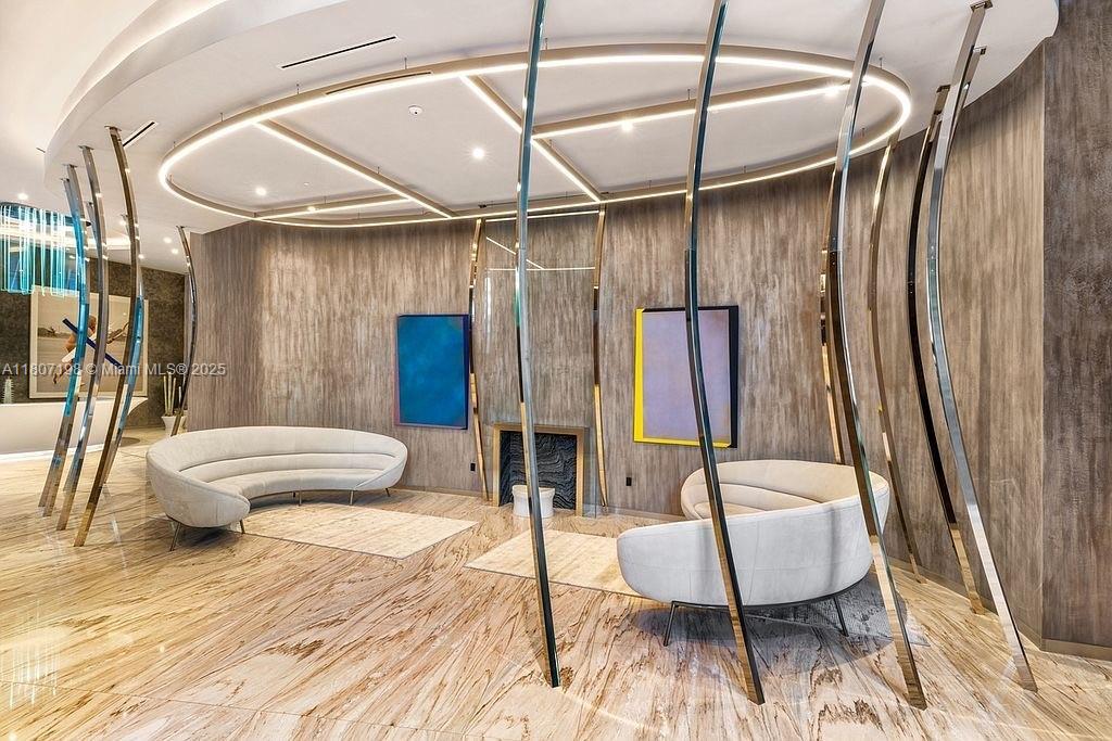 A modern lobby features curved white sofas, metallic vertical accents, and marble flooring — 1000 Brickell Plz # 2705, Miami FL 33131, MIAMI, FL