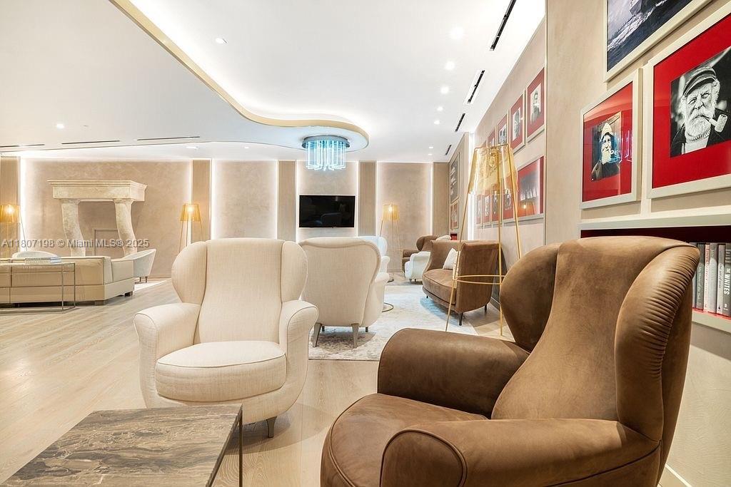 A modern lounge area features cream and brown armchairs, recessed lighting, and framed wall art — 1000 Brickell Plz # 2705, Miami FL 33131, MIAMI, FL