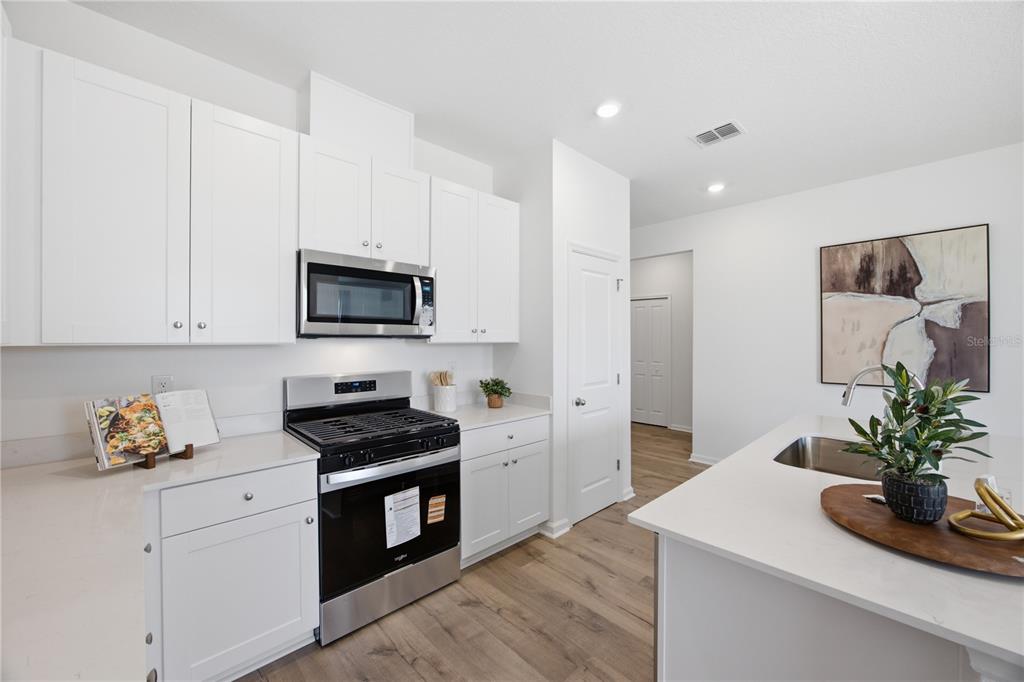 A modern kitchen features white cabinets, stainless steel appliances, and a white quartz island — 5731 HIAWASSEE ROAD, OKAHUMPKA, FL