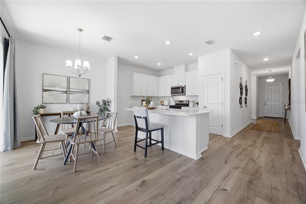 A bright kitchen and dining area with white cabinetry, a center island, and wood flooring — 5731 HIAWASSEE ROAD, OKAHUMPKA, FL