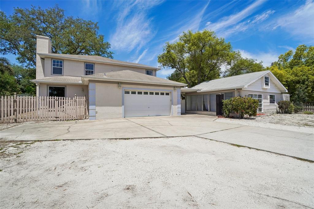 A two-story house with a garage and an attached single-story structure under a blue sky — 3220 COUNTY ROAD 1, DUNEDIN, FL