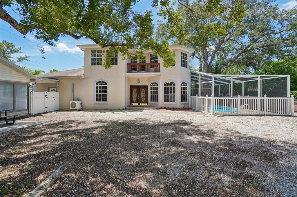 A two-story house with a balcony, arched windows, and a screened-in pool in the backyard — 3220 COUNTY ROAD 1, DUNEDIN, FL