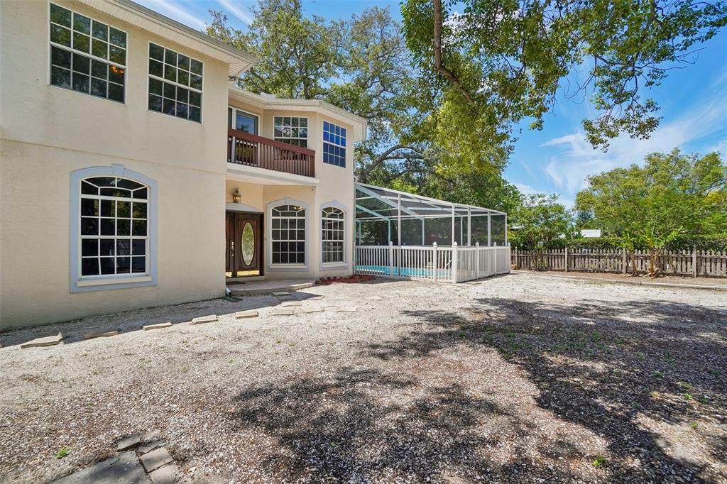 The exterior of a two-story house features a screened-in pool and a gravel yard — 3220 COUNTY ROAD 1, DUNEDIN, FL