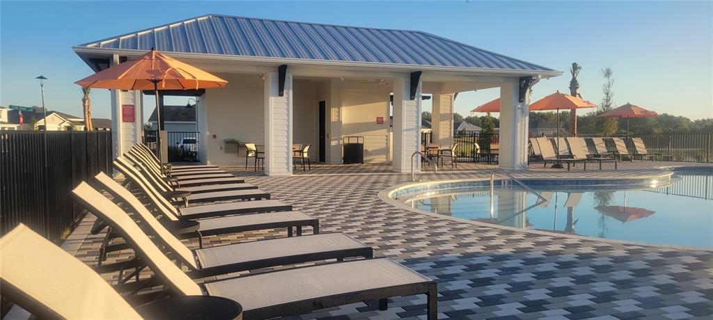 A pool deck features lounge chairs, orange umbrellas, and a covered pavilion with a metal roof — 3901 109TH STREET EAST, PALMETTO, FL