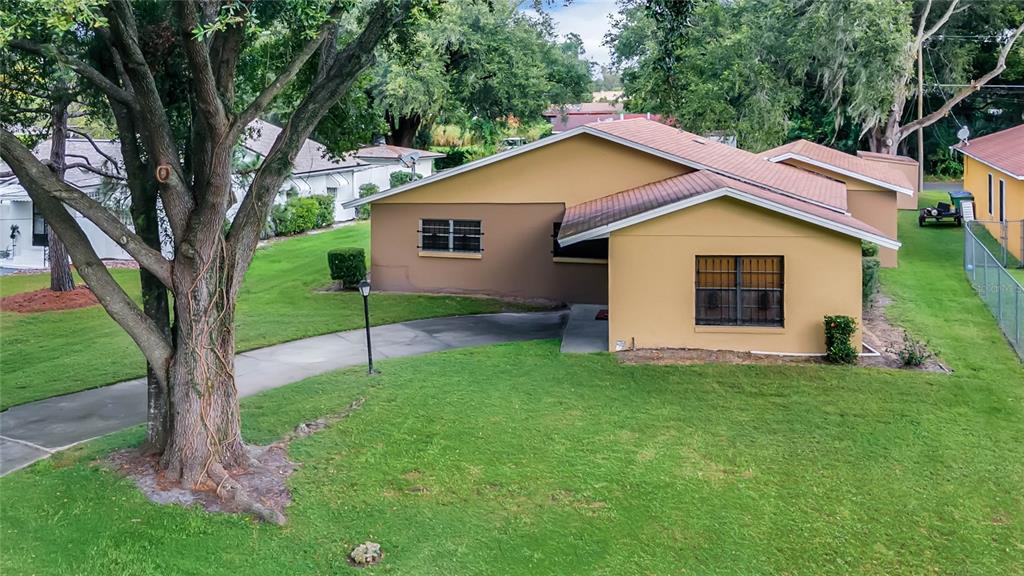 An exterior view of a tan, single-story house with a large tree and concrete driveway — 209 BAYSHORE DRIVE, ORLANDO, FL