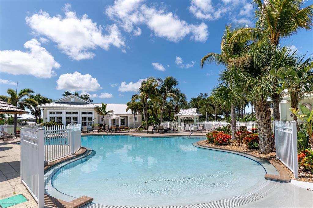 A swimming pool with a zero-entry edge is surrounded by palm trees and a building — 10521 AMBERJACK WAY UNIT 303, ENGLEWOOD, FL