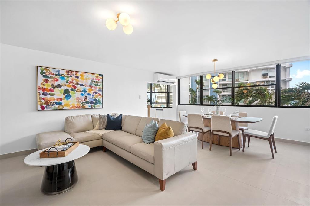 A bright living and dining area features a beige sectional sofa, marble table, and windows — 2 Condado Princess WASHINGTON UNIT 103, SAN JUAN, PR