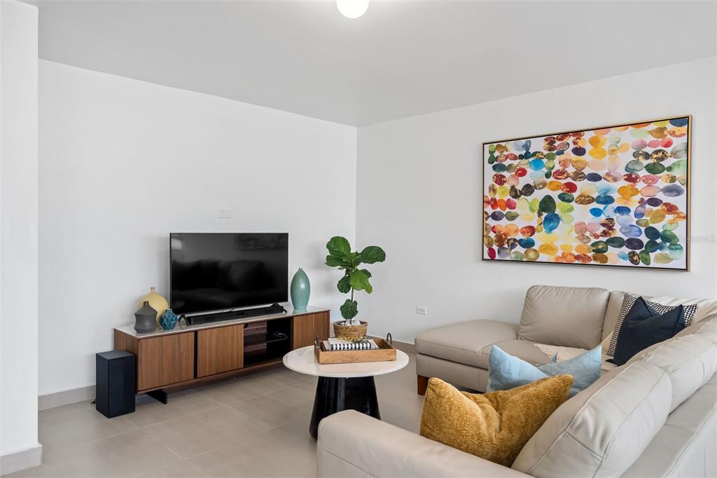A living room features a beige sectional sofa, a wooden media console, and colorful wall art — 2 Condado Princess WASHINGTON UNIT 103, SAN JUAN, PR