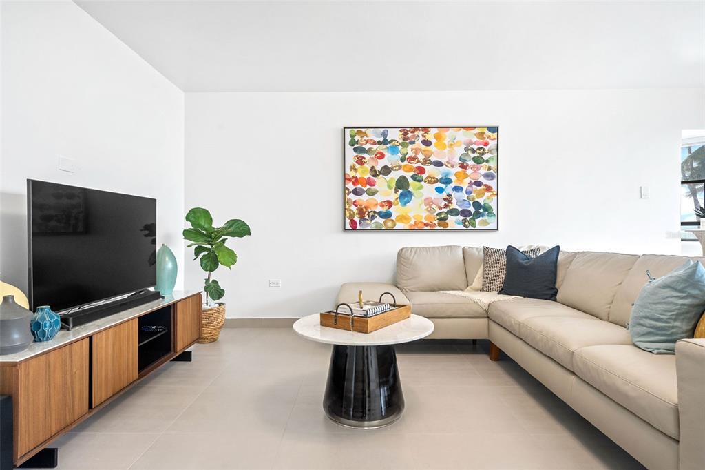 A living room features a beige sectional sofa, a round coffee table, and a television console — 2 Condado Princess WASHINGTON UNIT 103, SAN JUAN, PR