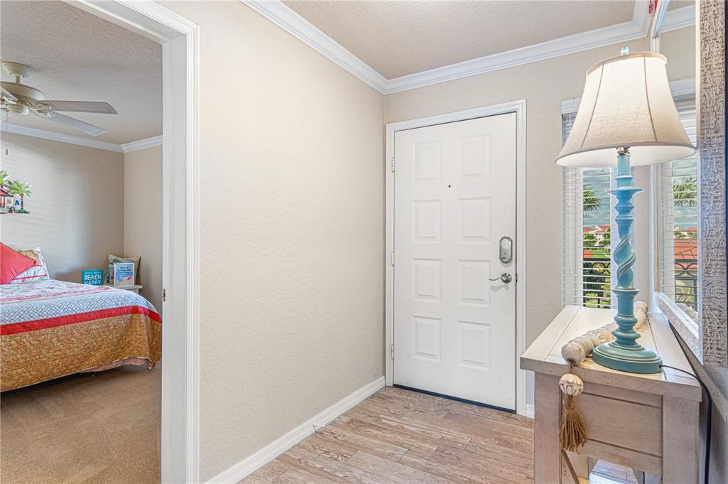 An entryway features a white door, wood-look tile flooring, and a console table with a lamp — 443 BOUCHELLE DRIVE UNIT 204, NEW SMYRNA BEACH, FL