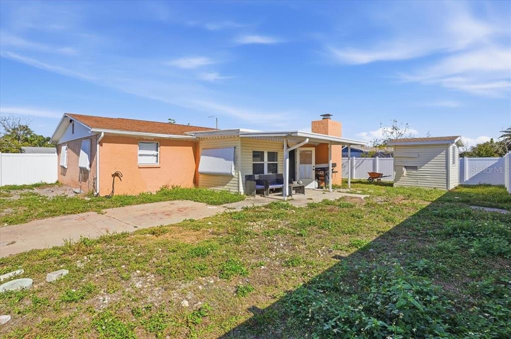 The exterior of a single-story house features orange stucco, yellow siding, and a covered patio — 3208 KILBURN ROAD, HOLIDAY, FL