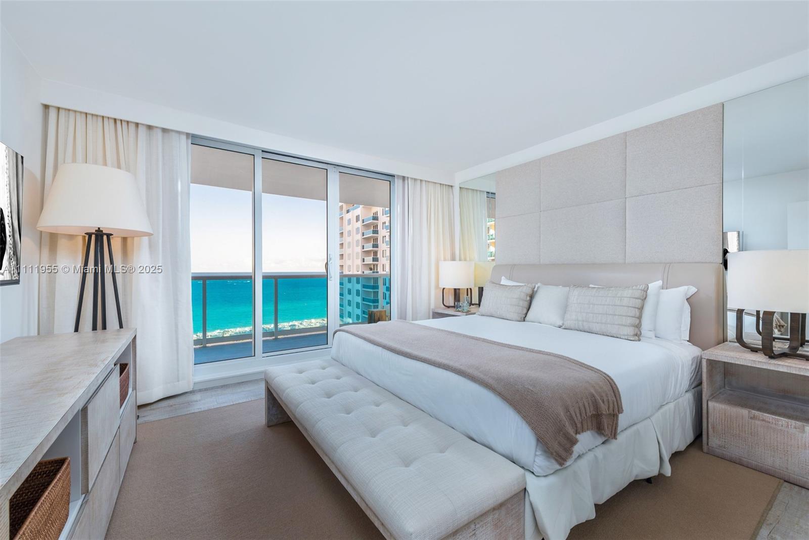 A bedroom features a king bed, a tufted bench, and a balcony overlooking the ocean — 102 24th St # 1144, Miami Beach FL 33139, MIAMI BEACH, FL