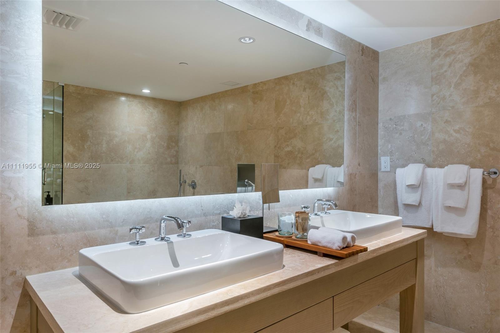 A modern bathroom features a double vanity with vessel sinks, stone walls, and a large mirror — 102 24th St # 1144, Miami Beach FL 33139, MIAMI BEACH, FL