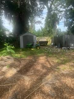 A backyard features a small storage shed, a riding lawnmower, and a wooden fence — 3835 8TH STREET S, ST PETERSBURG, FL