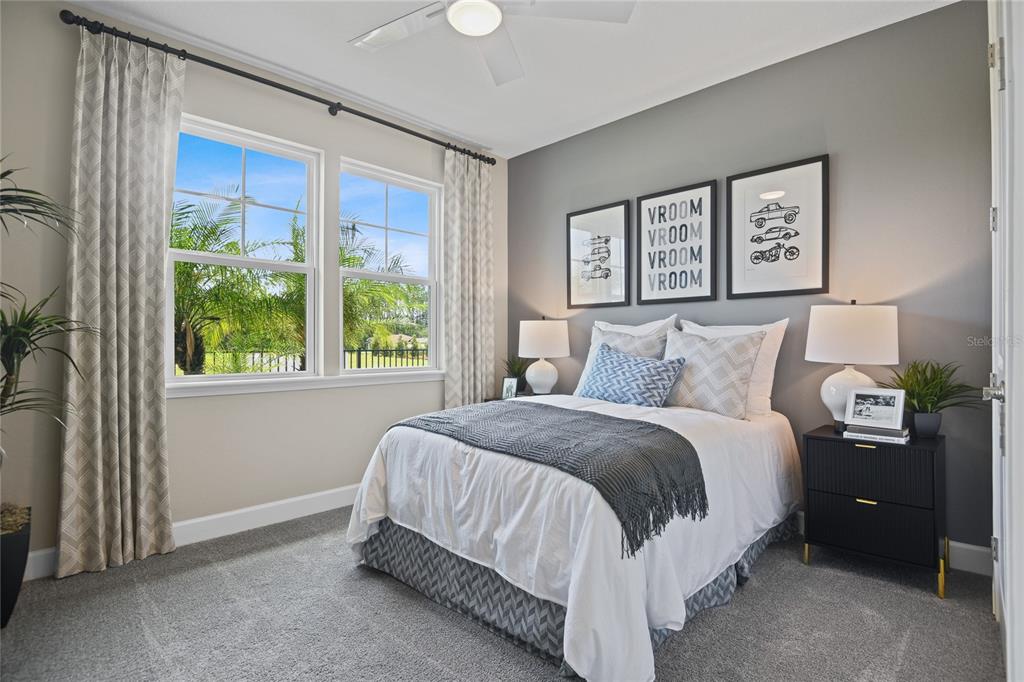 A bedroom features a bed with a gray throw, framed wall art, and two windows — 57 PONCE PRESERVE DRIVE, PALM COAST, FL