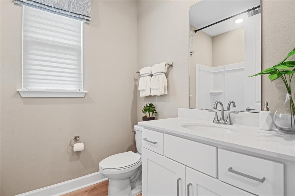 A bathroom features a white vanity, a toilet, a window with blinds, and a mirror — 57 PONCE PRESERVE DRIVE, PALM COAST, FL