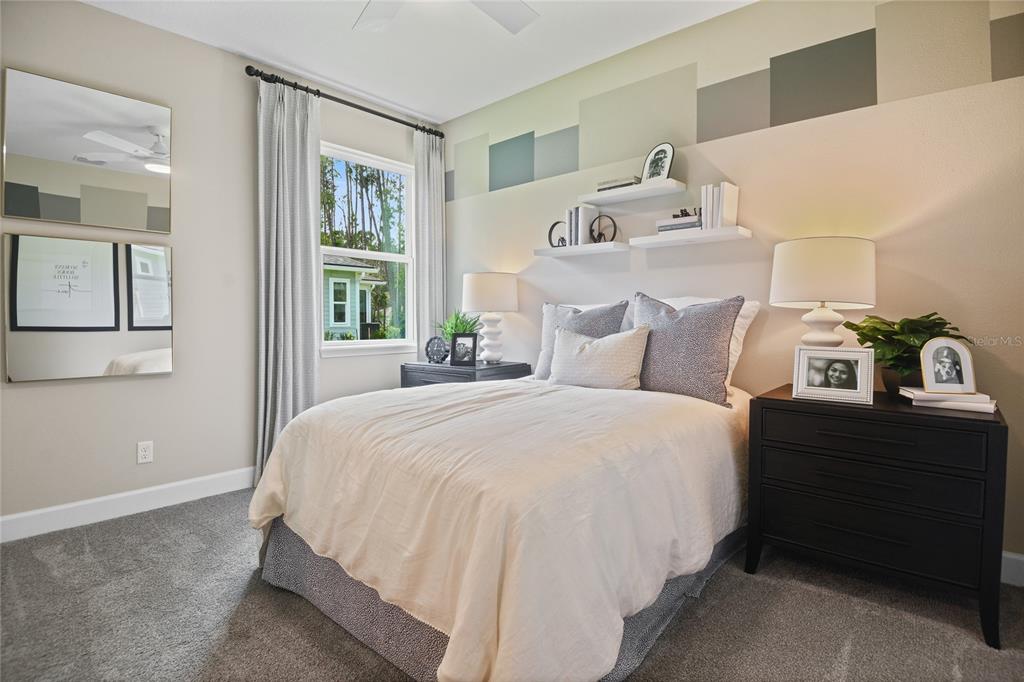 A bedroom features a bed with neutral bedding, two nightstands, wall shelves, and a window — 57 PONCE PRESERVE DRIVE, PALM COAST, FL