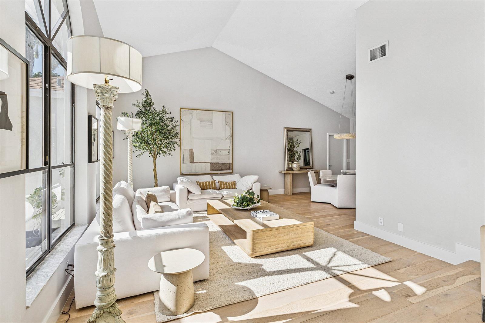 A bright living room features vaulted ceilings, white sofas, a wooden coffee table, and hardwood floors — 48 Harbour Drive N, Ocean Ridge FL 33435, OCEAN RIDGE, FL