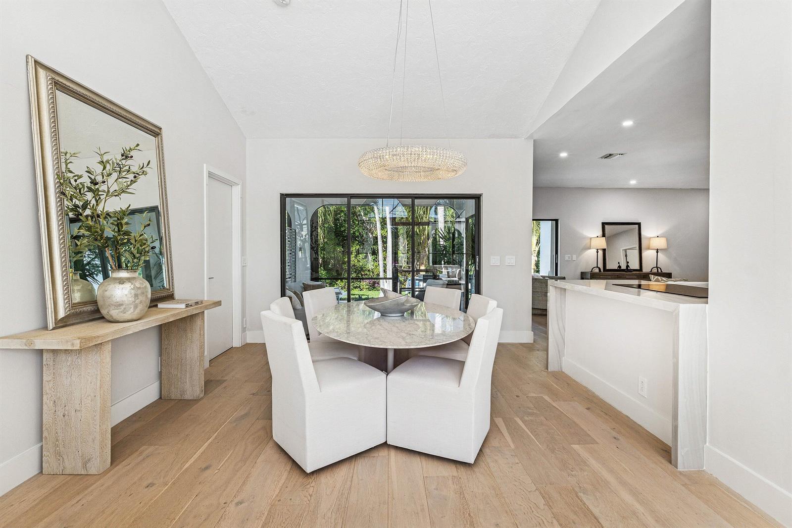 A dining room features a round marble table, white upholstered chairs, and a crystal chandelier — 48 Harbour Drive N, Ocean Ridge FL 33435, OCEAN RIDGE, FL