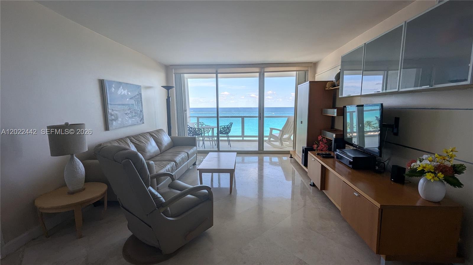 A living room with marble floors features a sofa, recliner, and balcony overlooking the ocean — 5161 Collins Ave # 1217, Miami Beach FL 33140, MIAMI BEACH, FL