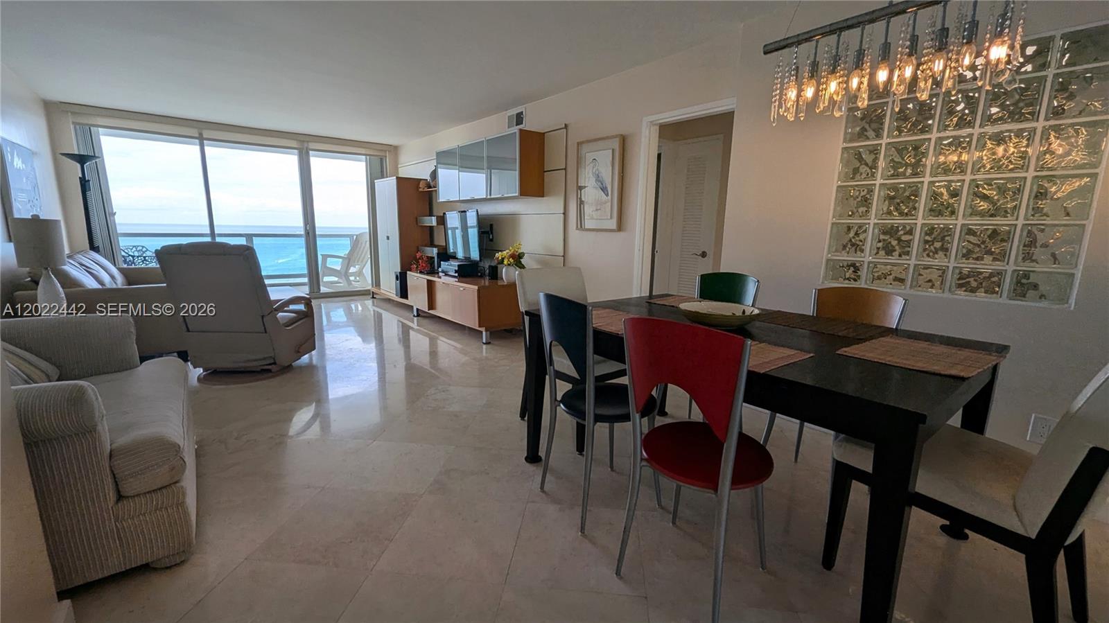 A living and dining area features marble floors, a glass block wall, and ocean views — 5161 Collins Ave # 1217, Miami Beach FL 33140, MIAMI BEACH, FL