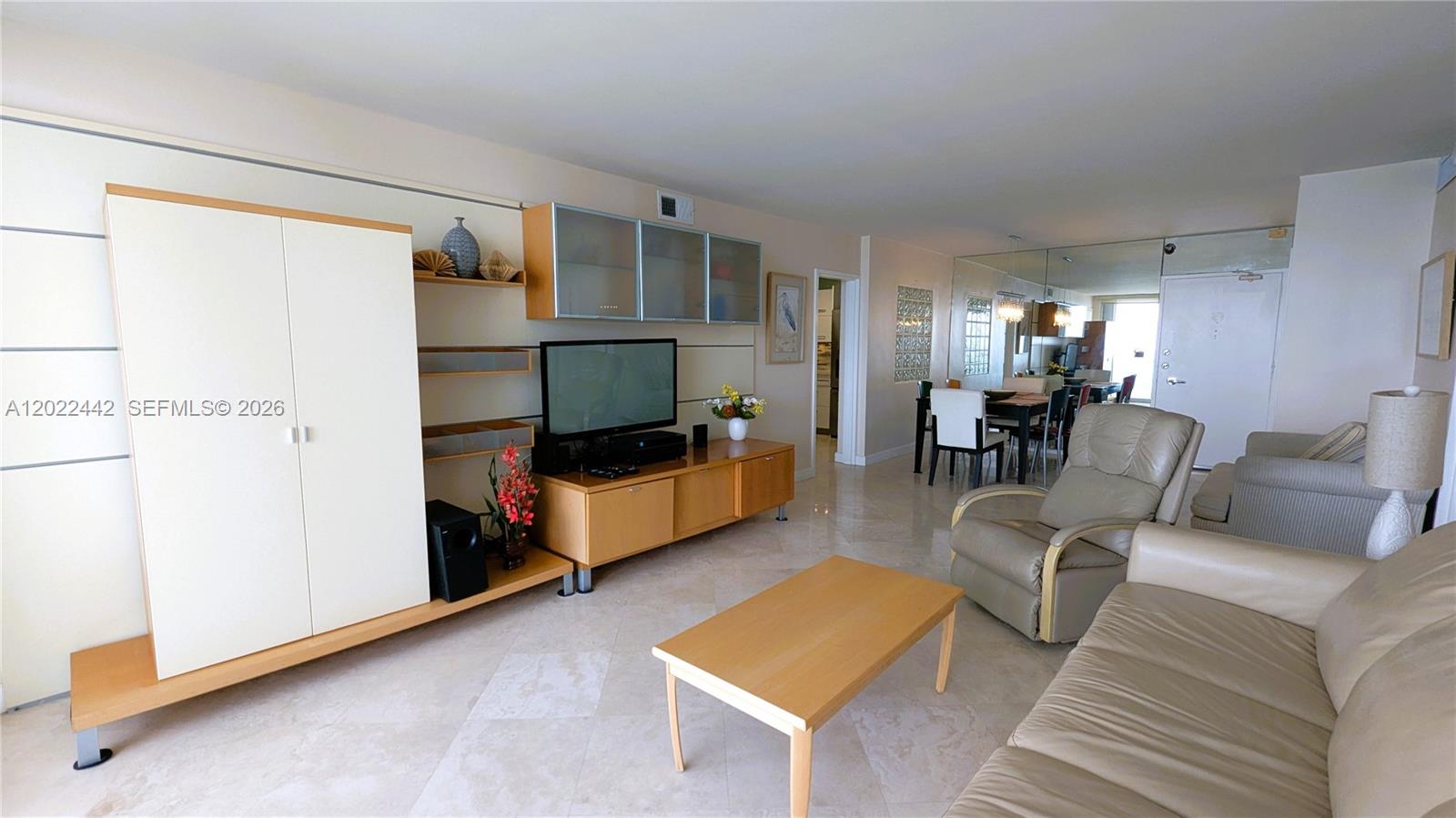A living room features light tile floors, a wooden media console, and a leather recliner — 5161 Collins Ave # 1217, Miami Beach FL 33140, MIAMI BEACH, FL