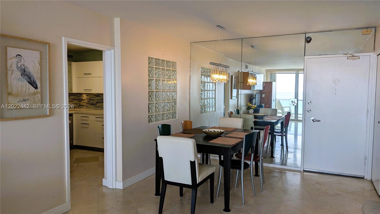 A dining area features a dark table, mixed chairs, a glass block wall, and mirrored panels — 5161 Collins Ave # 1217, Miami Beach FL 33140, MIAMI BEACH, FL