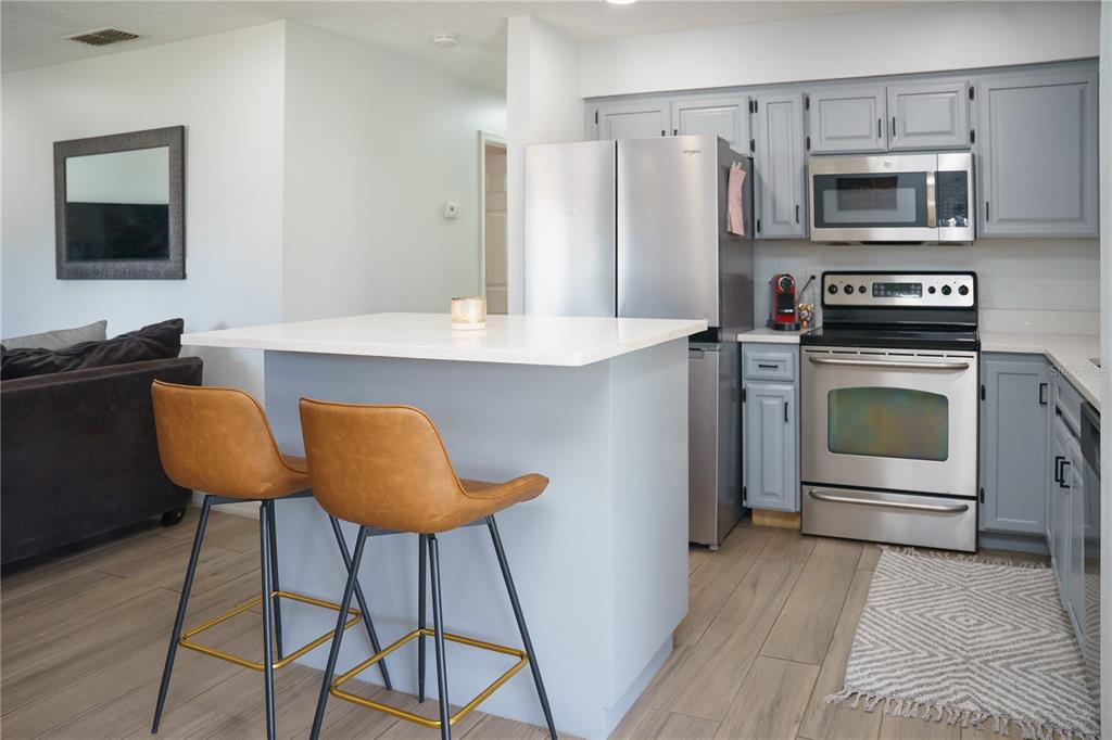 A kitchen features gray cabinets, stainless steel appliances, a white island, and two brown stools — 6552 S WEST SHORE CIRCLE, TAMPA, FL