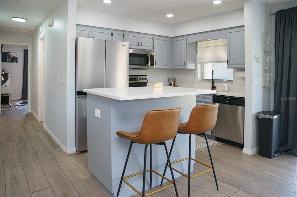 A kitchen features light blue cabinets, stainless steel appliances, a white island, and two stools — 6552 S WEST SHORE CIRCLE, TAMPA, FL