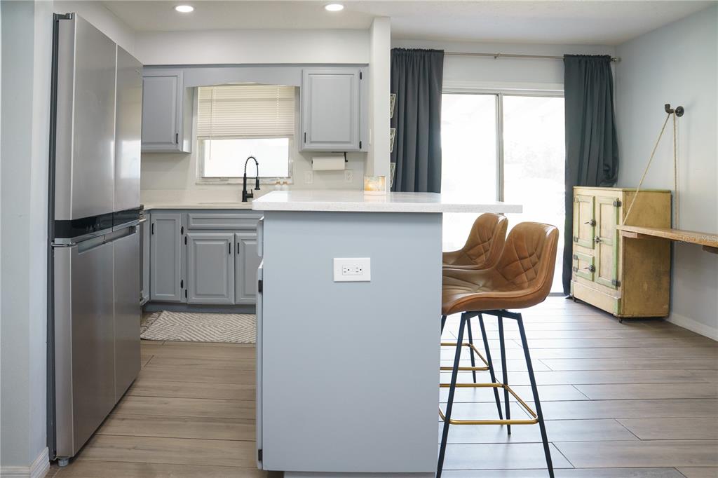 A kitchen features light gray cabinets, a central island with bar stools, and stainless appliances — 6552 S WEST SHORE CIRCLE, TAMPA, FL