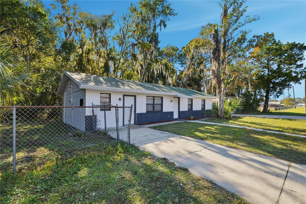 A single-story house with a white and dark gray exterior, metal roof, and concrete driveway — 1915 BRONSON STREET, PALATKA, FL