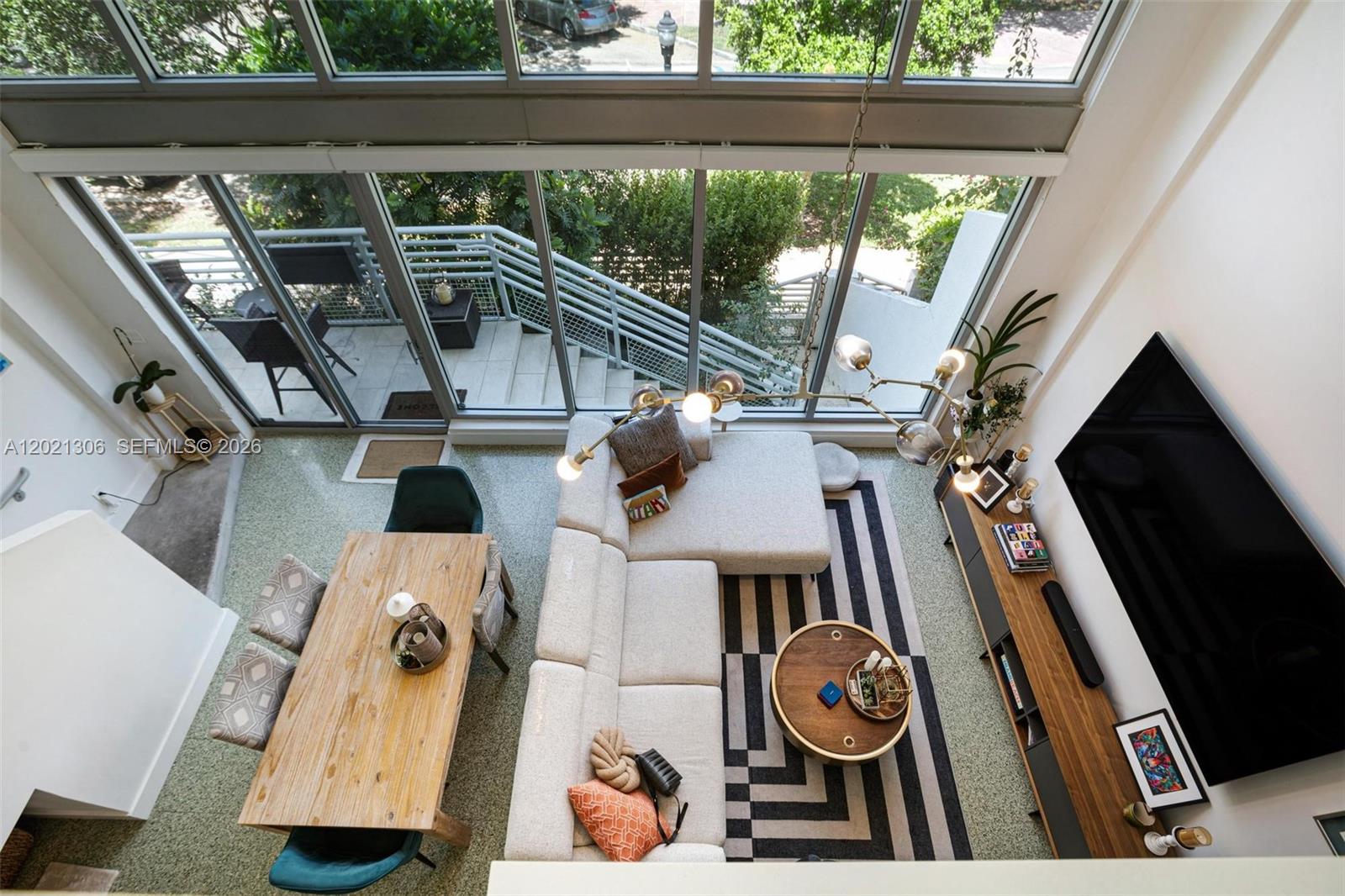 A high-angle view of a modern living and dining area with floor-to-ceiling windows — 245 Michigan Ave # 5, Miami Beach FL 33139, MIAMI BEACH, FL