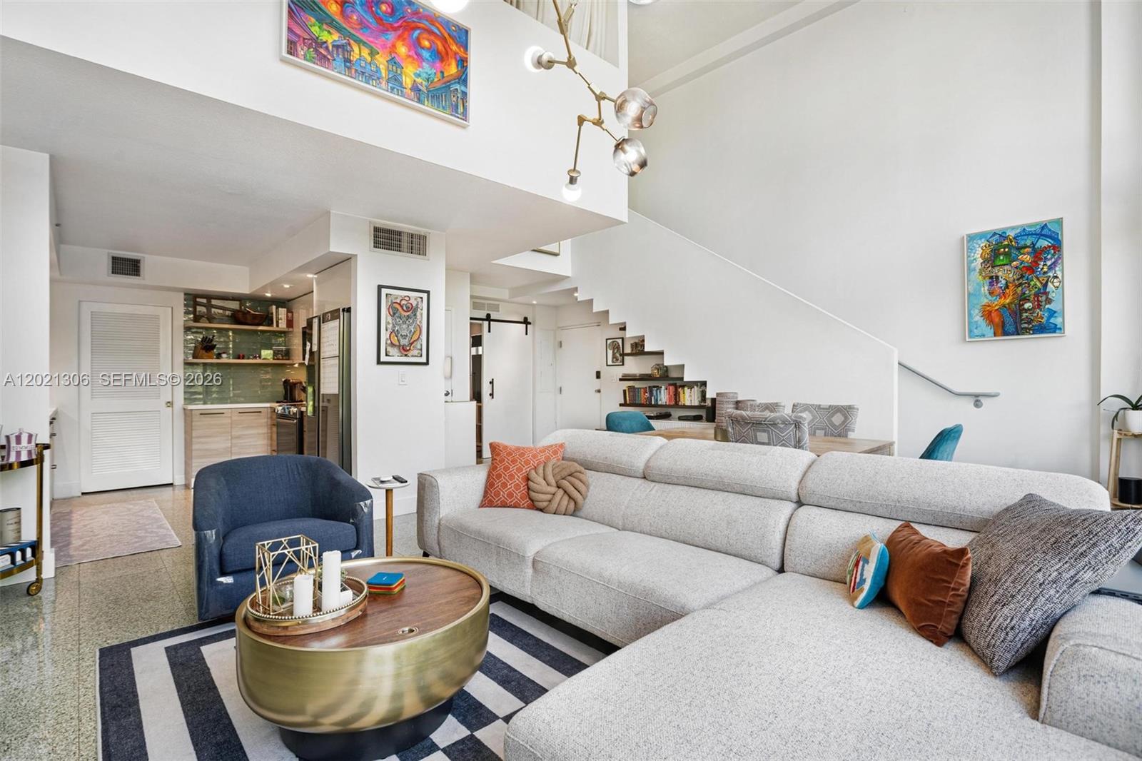 A living room features a large sectional sofa, a round coffee table, and a staircase — 245 Michigan Ave # 5, Miami Beach FL 33139, MIAMI BEACH, FL