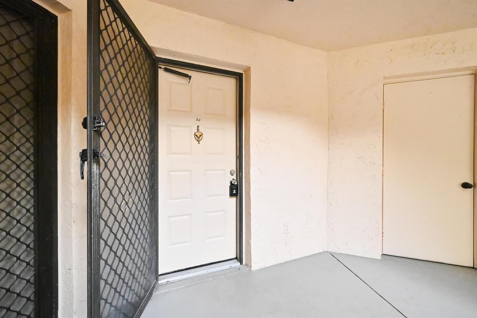 An exterior view shows a white front door with a screen door and a utility closet — 2013 NE Collins Circle # 50, Jensen Beach FL 34957, JENSEN BEACH, FL